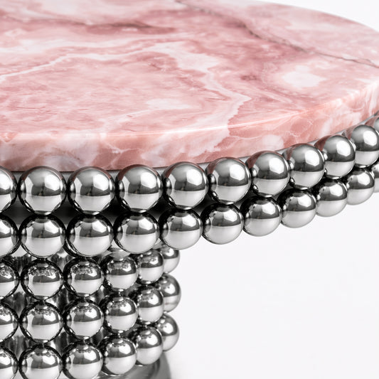 Round pink onyx dining table featuring sculptural chrome stainless steel sphere pedestal.