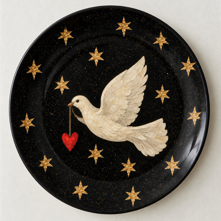 A round black decorative plate with gold speckles, featuring a white dove holding a small red heart, surrounded by gold stars.