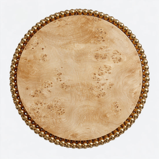 Sculptural dining table featuring swirling poplar burl top and gold sphere pedestal.