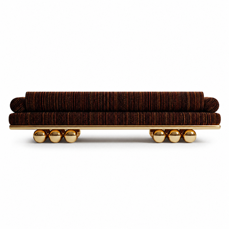 Sculptural Lustra Sofa by Hekla Property, designed with a low elongated silhouette, rounded cushions, and reflective gold metal details.