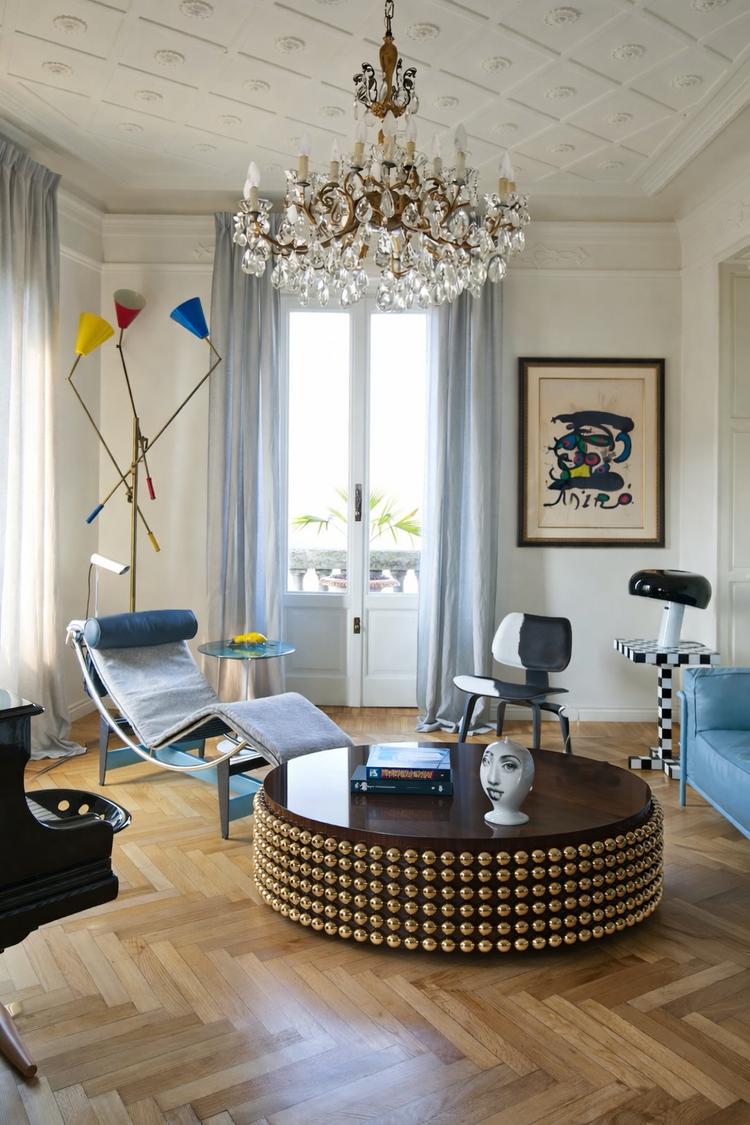 Lustra coffee table in wenge veneer with gold sphere base placed in a modern living room setting, designed by Railis Kotlevs