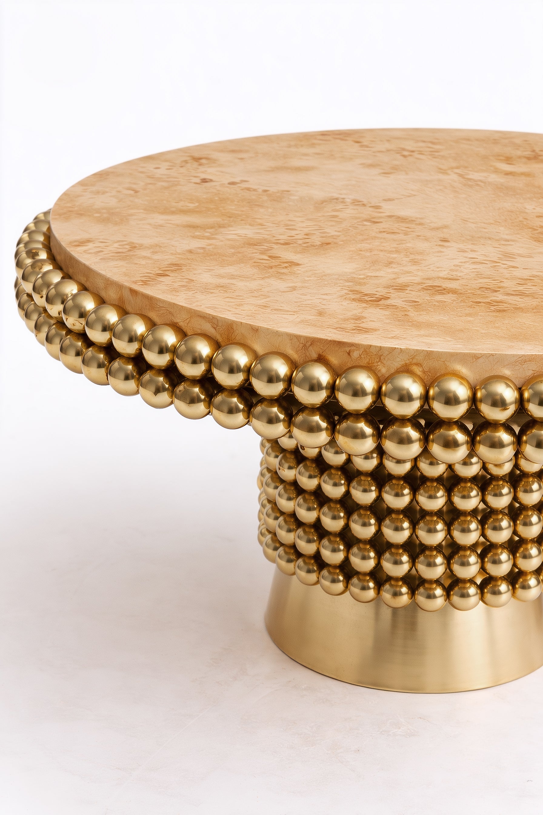 Luxury round dining table combining organic wood grain and reflective metal spheres.