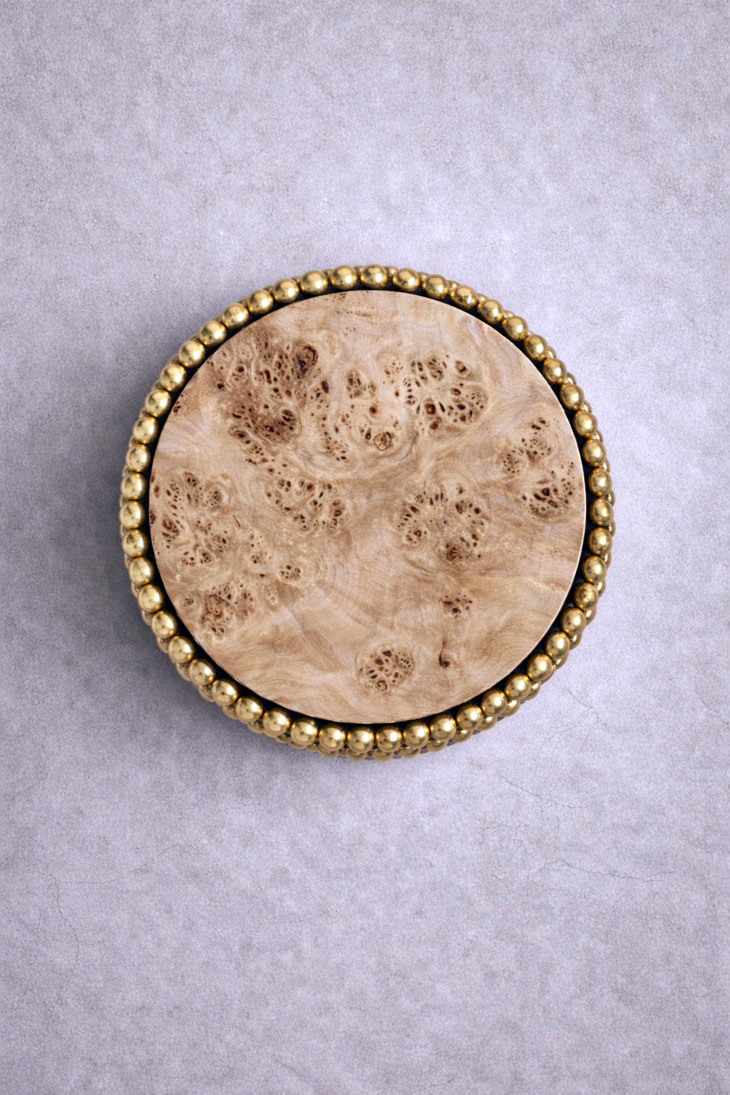 Round side table with reflective gold sphere base and poplar burl top, designed by Railis Kotlevs