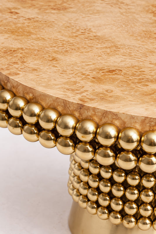 Close view of poplar burl veneer tabletop with architectural brass sphere detailing.