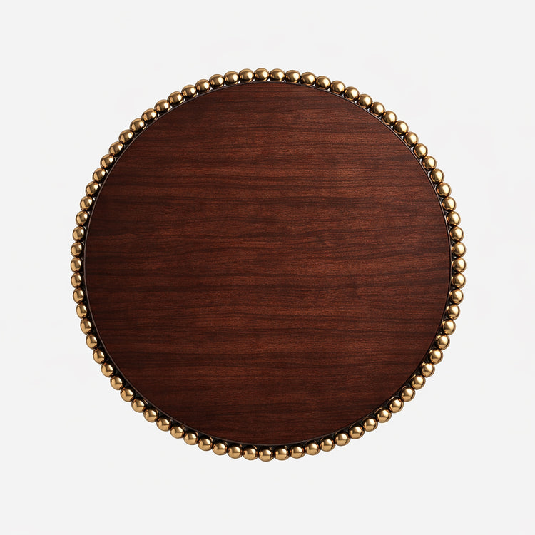 Top-down view of the Lustra round dining table displaying the smooth dark veneer surface framed by a ring of polished gold spheres.