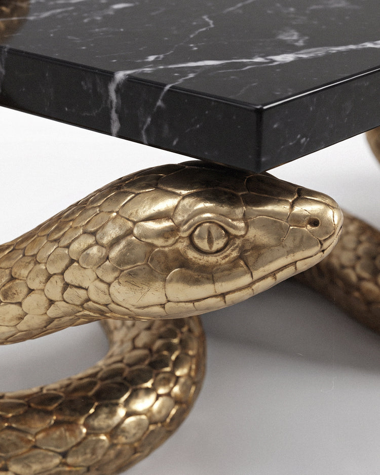 Detail view of the sculpted serpent scales beneath the black Nero marble tabletop.