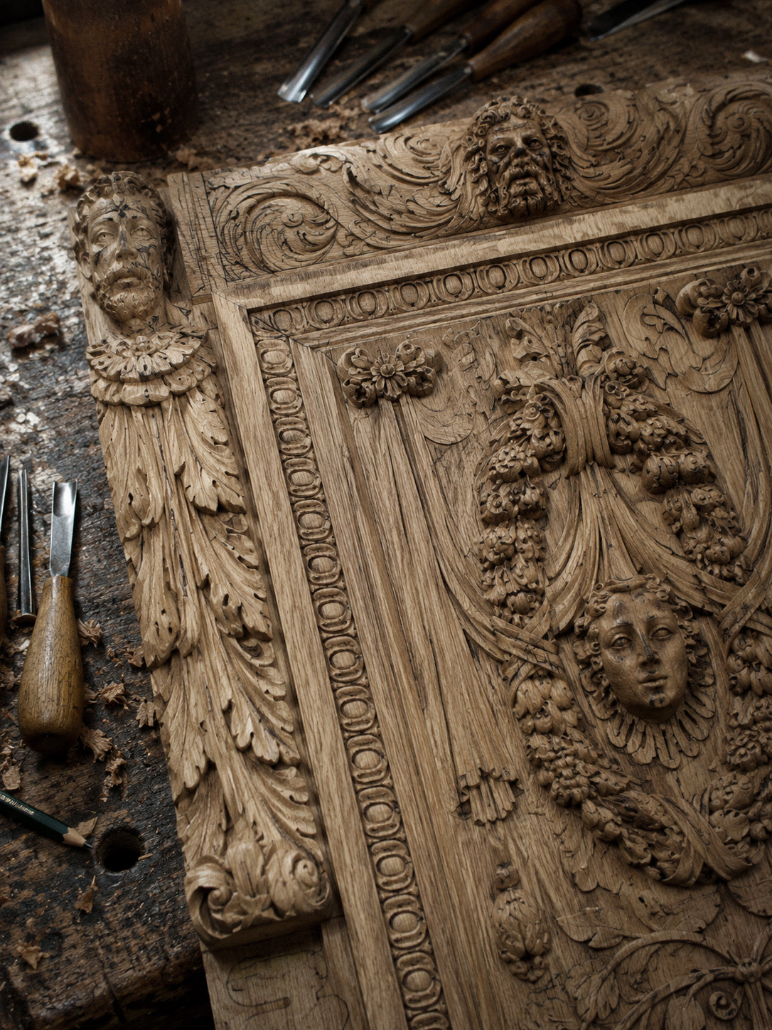 Close-up of black hand-carved wooden cabinet details with sculptural faces and floral ornament.