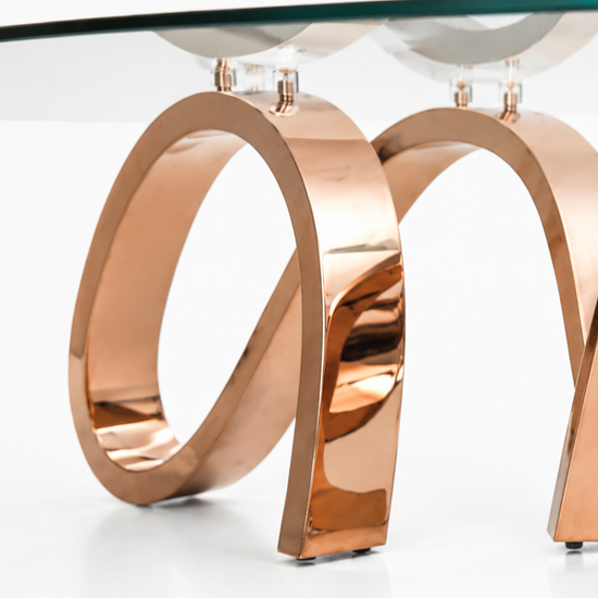 Close-up of Apate Coffee Table showing polished copper-plated metal curves and glass fixing details.