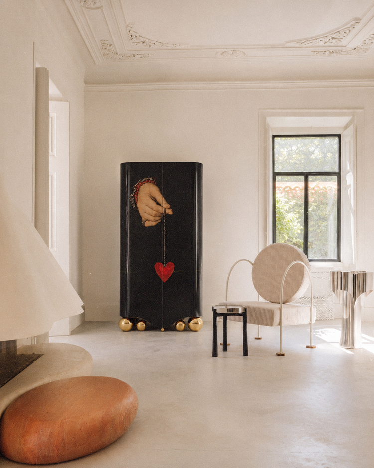 Luxury black drinks cabinet with romantic hand-and-heart artwork and sculptural polished gold sphere base.