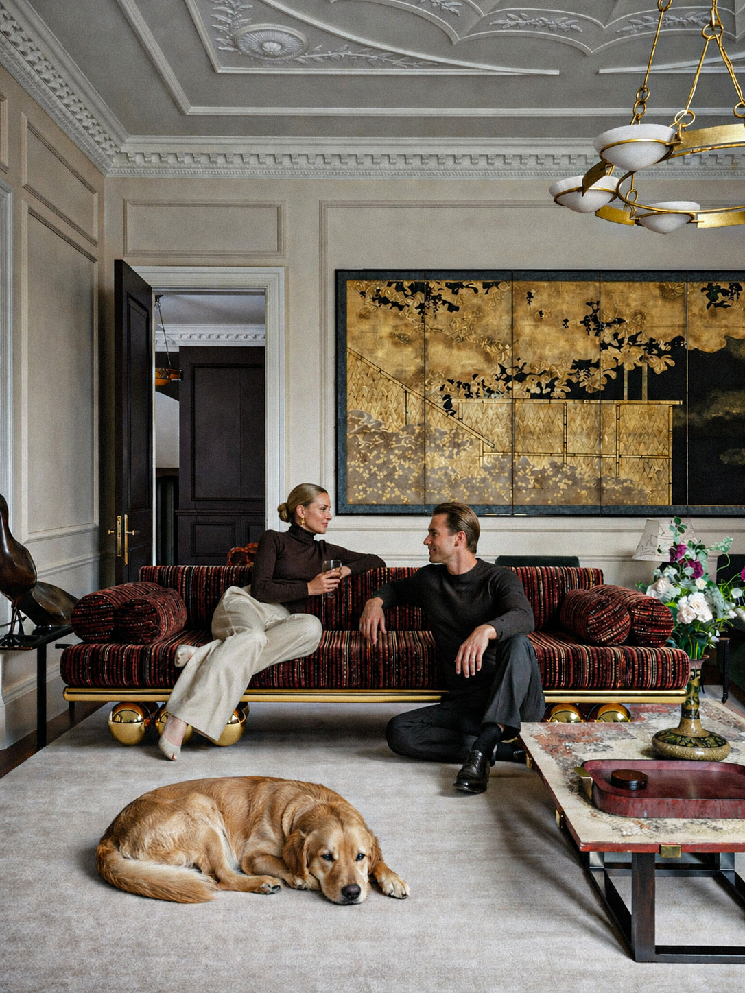 Two people sitting on a plush sofa in an elegant living room with a dog lying on the floor. Lustra sofa