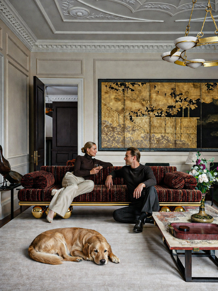 Two people sitting on a plush sofa in an elegant living room with a dog lying on the floor. Lustra sofa