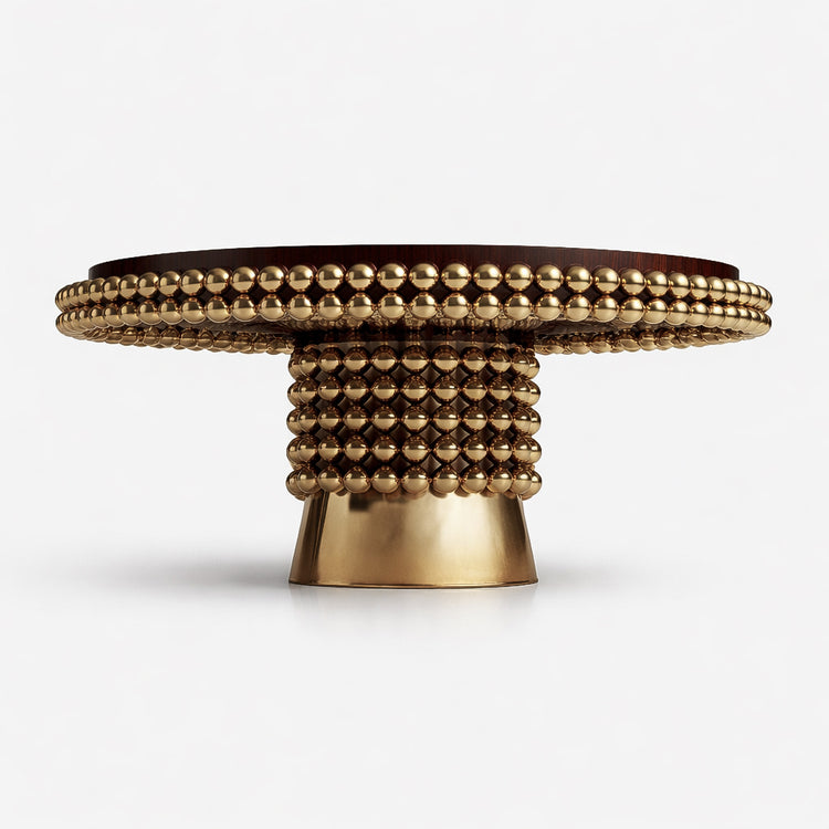 Close-up detail of the Lustra table edge showing the dark wood veneer and double row of polished gold spheres with reflective finish.