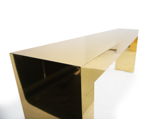 Contemporary gold console reflecting surrounding architecture and interior details.