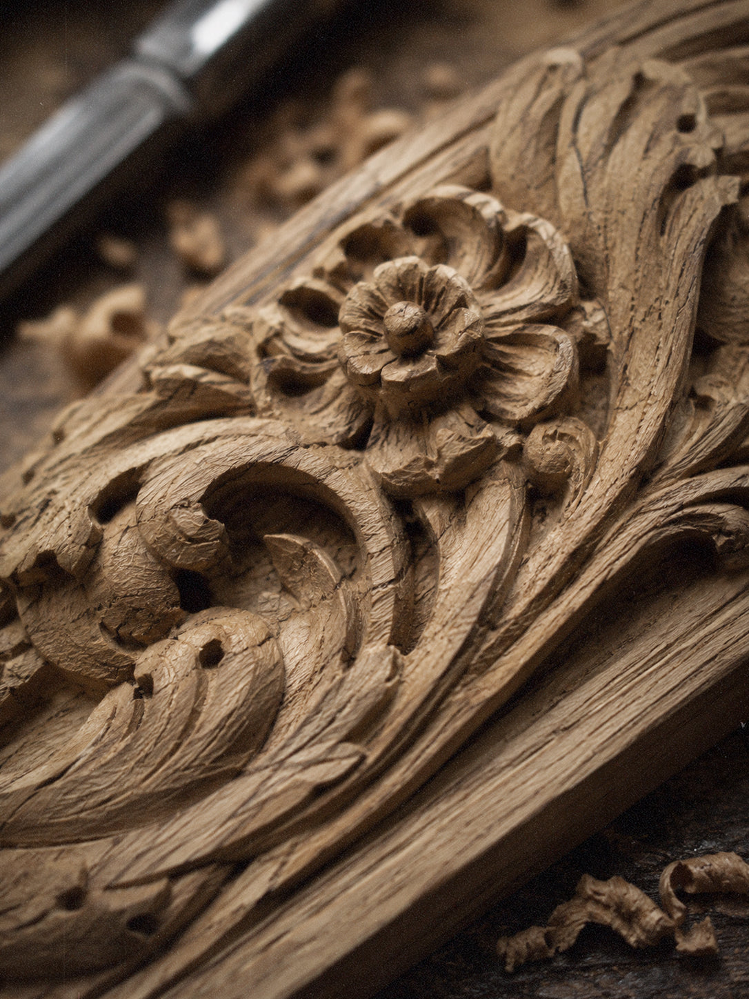 Close-up of black hand-carved wooden cabinet details with sculptural faces and floral ornament.