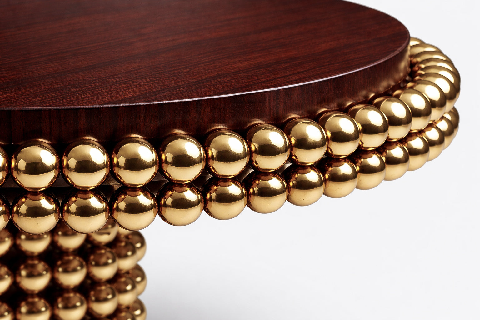 Low-angle perspective of the Lustra dining table emphasizing the sculptural gold sphere structure and solid brass pedestal base.