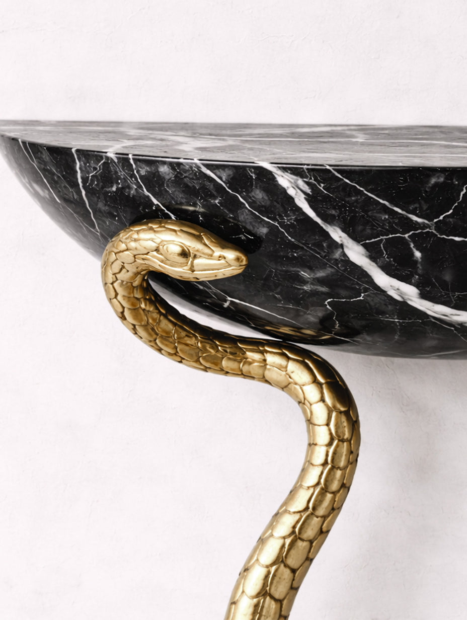 Decorative console table with gold snake design on a marble surface