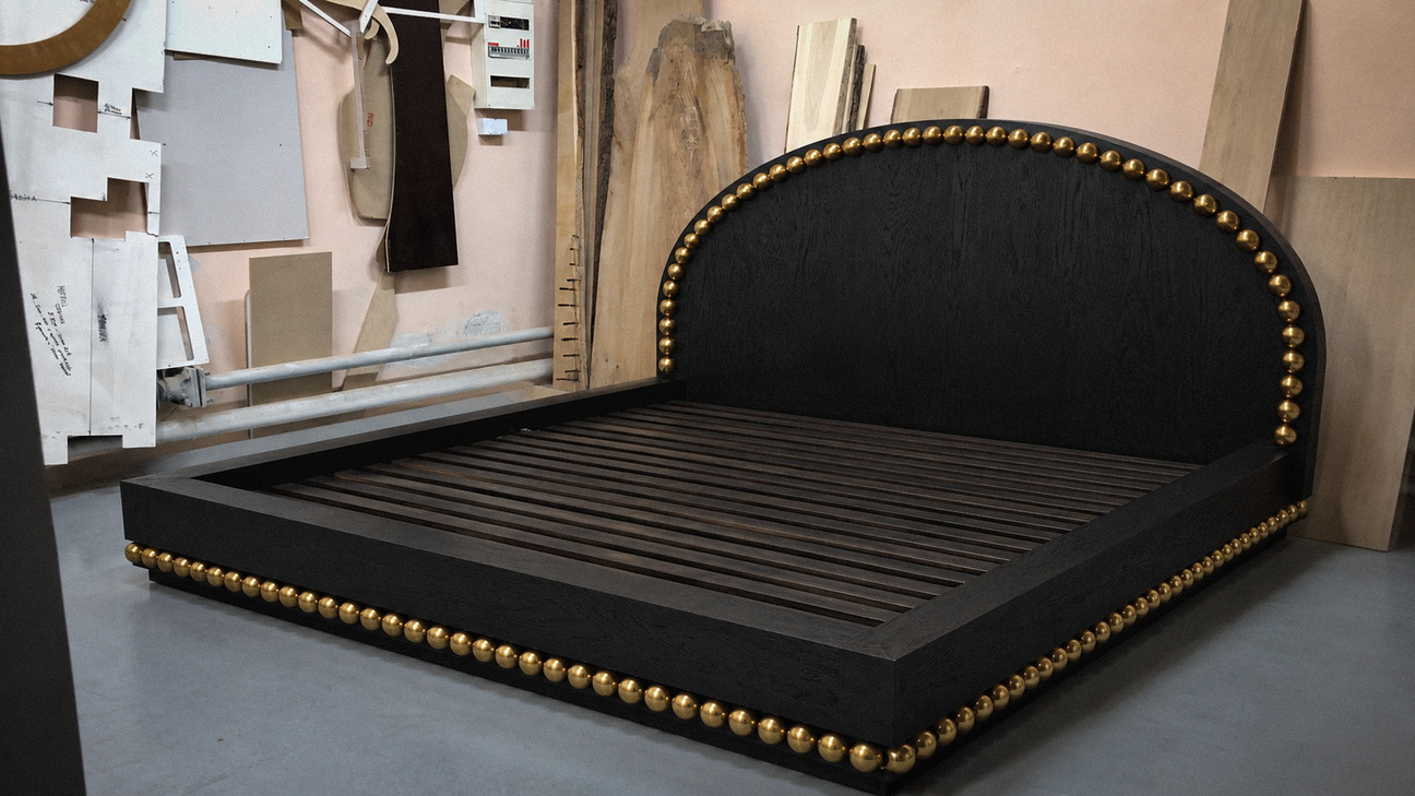 Black upholstered bed with gold accents in a room setting