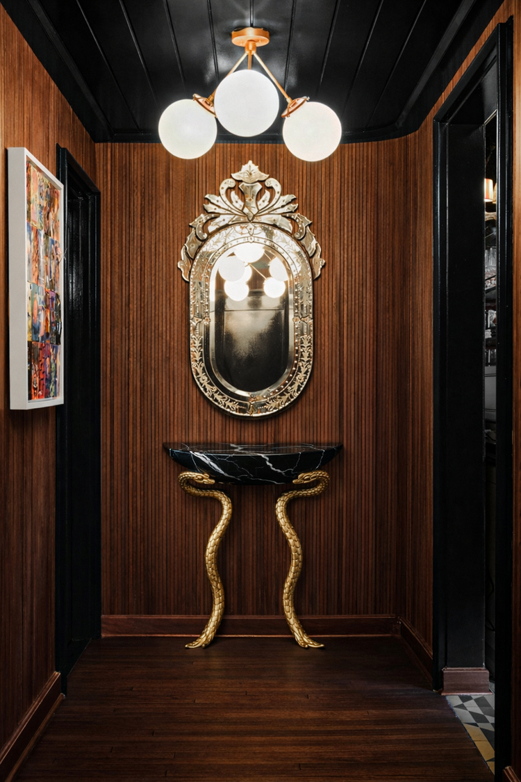 Black Nero marble statement console with detailed brass serpent structure.