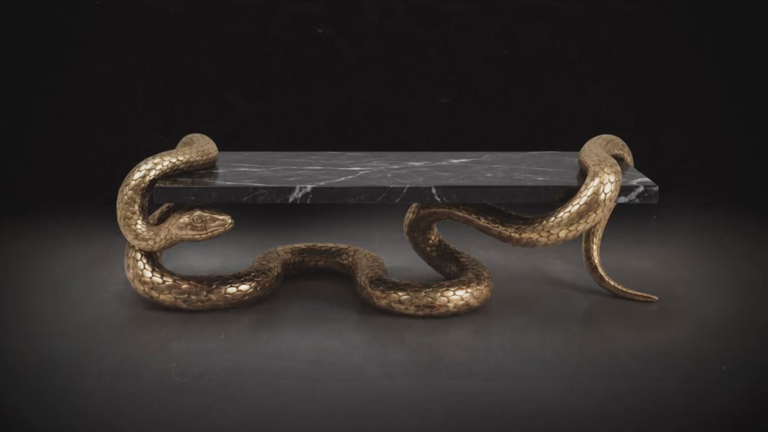 Luxury sculptural coffee table with black marble surface and handcrafted serpent-inspired metal base.