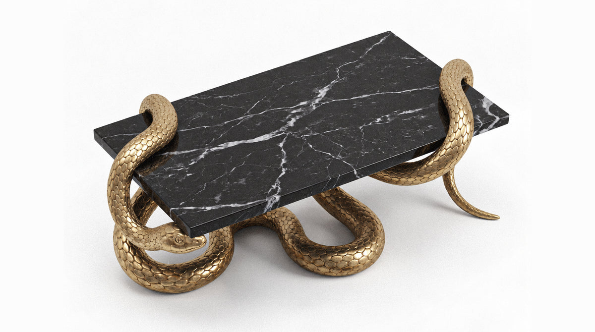 A modern coffee table featuring a rectangular black marble top with white veining, supported by four sculptural gold snakes wrapped around the base, shown on a clean white background.